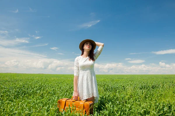 夏のシーズンに麦畑でスーツケース立って美しい赤毛の女の子 — ストック写真