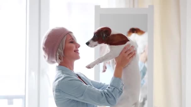 年轻的女孩在贝雷帽与短头发打扮近镜与狗在家里 — 图库视频影像