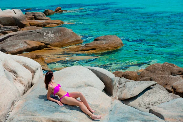 Ung vacker flicka i rosa bikini på en sten — Stockfoto