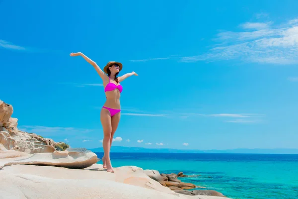 Jeune belle fille en bikini rose sur un rocher — Photo