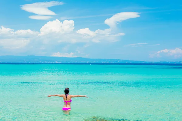 Menina de biquíni rosa em pé em uma água na praia — Fotografia de Stock