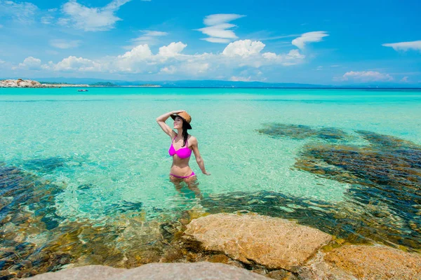 Chica en bikini rosa de pie en un agua en la playa —  Fotos de Stock
