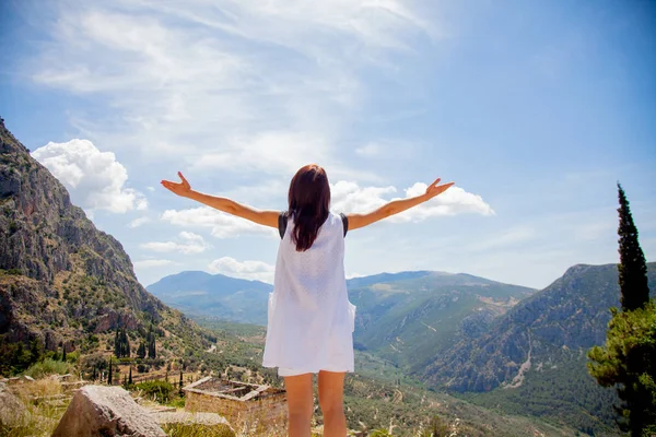Chica joven en ropa blanca de pie en la roca en Grecia —  Fotos de Stock