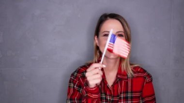 Gri arka plan üzerinde ABD bayrağı sallayarak kadın