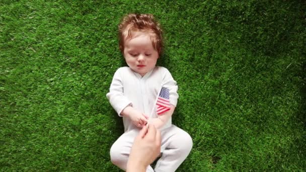 Small Boy Laying Fresh Green Grass Female Hand Giving Flag — Stock Video