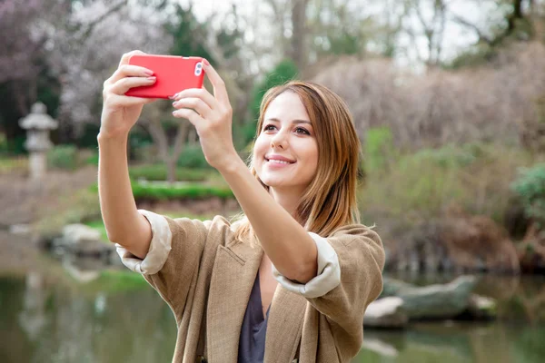 Рыжая девушка делает селфи с мобильного телефона — стоковое фото