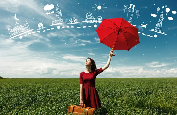 Молодая женщина с чемоданом и зонтиком — стоковое фото