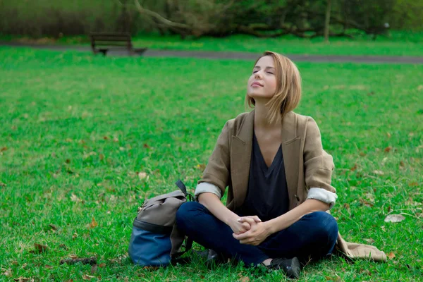 Chica sentado en verde hierba en un parque —  Fotos de Stock