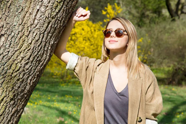 Ragazza in occhiali da sole in piedi vicino a un albero — Foto Stock