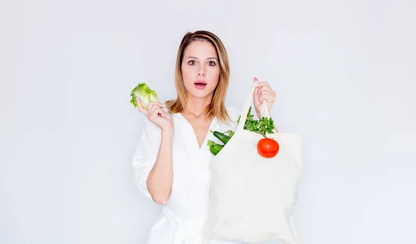 Mulher surpreso segurando saco com vegetais diferentes — Fotografia de Stock