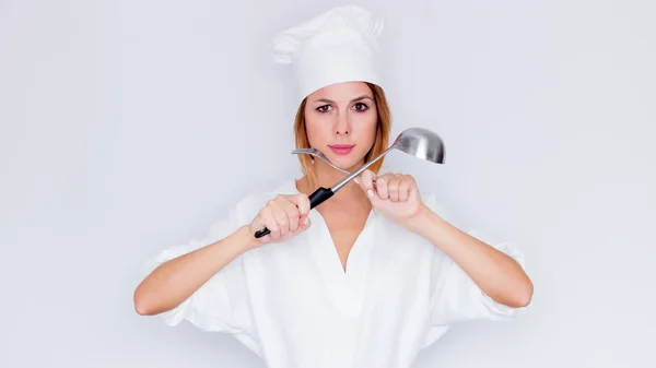 Mulher em cozinheiro uniforme segurando utensílios de cozinha — Fotografia de Stock