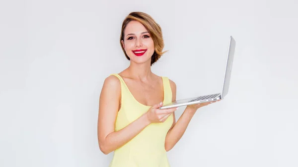 Mädchen in gelbem Kleid mit Laptop — Stockfoto