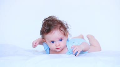 küçük bebek hafif giysiler içinde bir yatakta yatarken