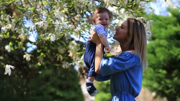 Jeune rousse mère et enfant ont un loisir au printemps magnolia jardin fleurissant le jour ensoleillé 
