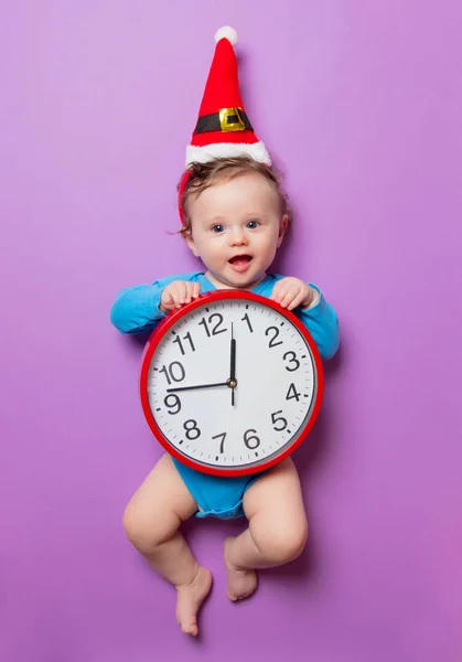Baby in Christmas hat with alarm clock — Stock Photo, Image