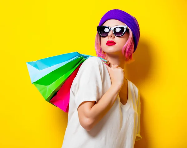 Chica joven con bolsas de compras sobre fondo amarillo — Foto de Stock