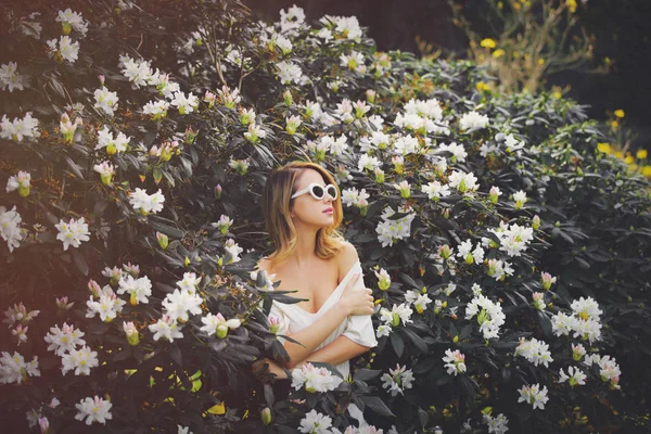 Mädchen mit weißer Sonnenbrille in der Nähe von Blumen — Stockfoto