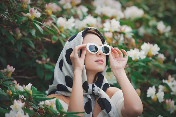 Zrzka dívka do bílého šátku poblíž květiny — Stock fotografie