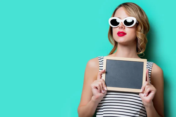 Jeune fille en lunettes de soleil avec tableau noir — Photo