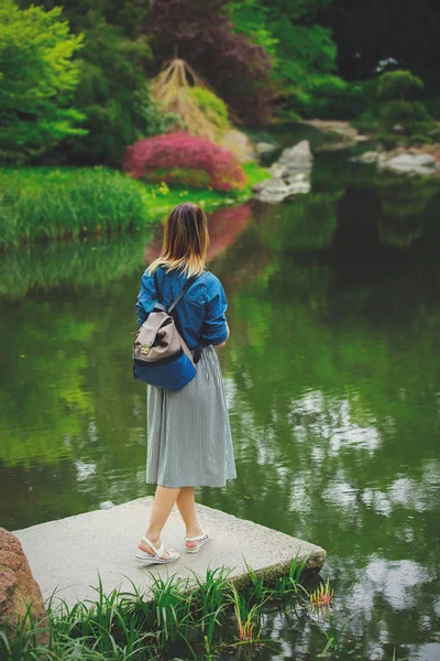 La ragazza elegante giovane ha un riposo vicino a uno stagno — Foto Stock