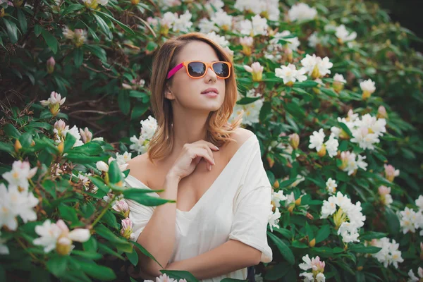 Mädchen mit weißer Sonnenbrille in der Nähe von Blumen — Stockfoto