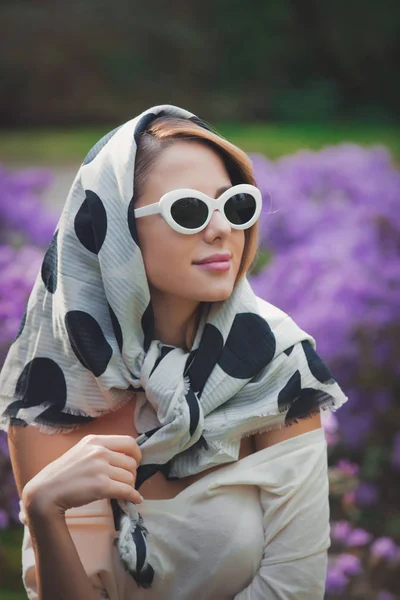 Menina em xale branco perto de flores roxas — Fotografia de Stock