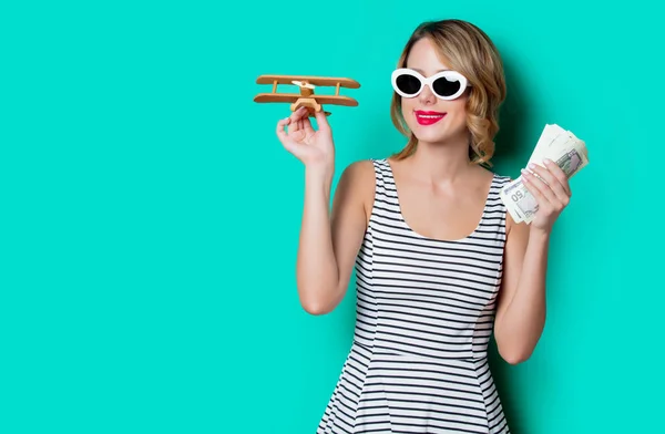 Meisje in zonnebril met geld en houten vliegtuig — Stockfoto