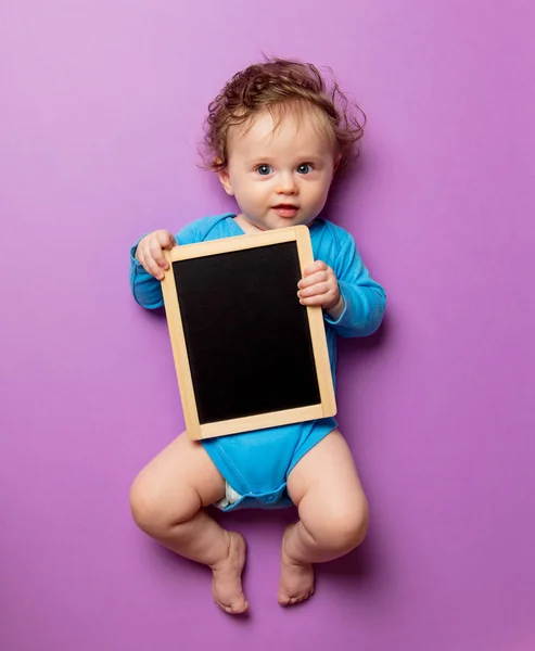 Pequeno bebê infantil com cabelo e quadro negro — Fotografia de Stock