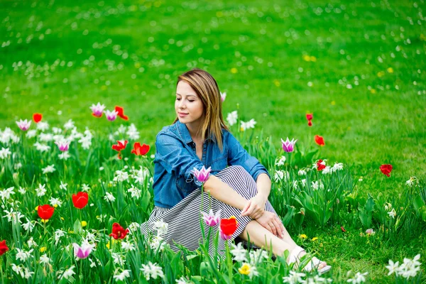 Menina ruiva jovem sentado no prado tulipas — Fotografia de Stock