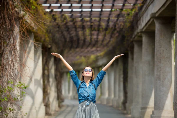 Девушка ходит по аллее с арками и колоннами — стоковое фото