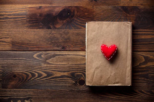 Libro y forma de corazón en mesa de madera — Foto de Stock