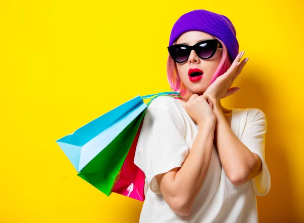 Chica joven con bolsas de compras sobre fondo amarillo — Foto de Stock