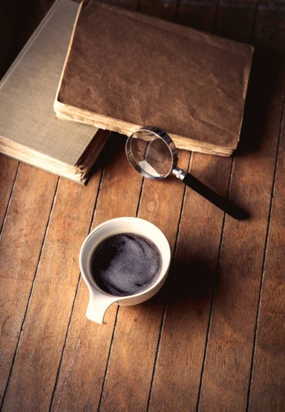 Белая чашка с кофе и книги с увеличителем — стоковое фото