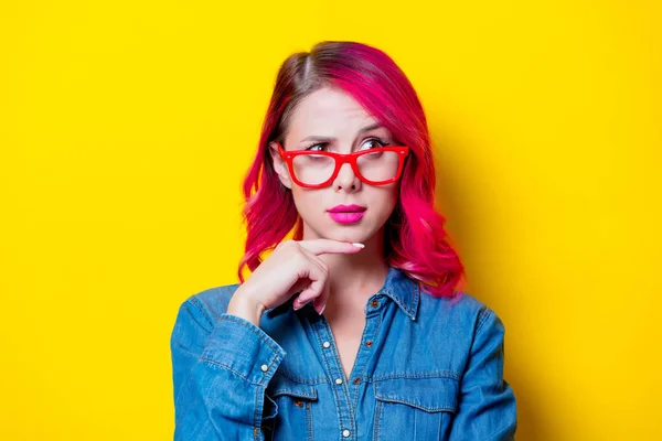 若いピンクの青いシャツと赤いメガネで髪の女の子 黄色の背景に分離された肖像画 — ストック写真