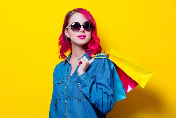 Renkli bir alışveriş torbaları tutan güneş gözlüklü kız — Stok fotoğraf