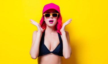 Genç saç kız bikini ve kap ile turuncu gözlük pink. Portre sarı arka plan üzerinde izole