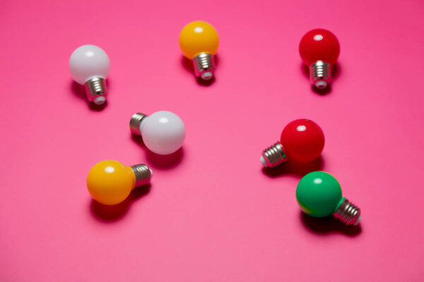 Group of colored lightbulbs on pink bakground