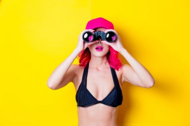 Genç saç kız bikini kap ve dürbün ile pink. Portre sarı arka plan üzerinde izole