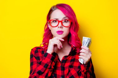 Genç saç kız para ile kırmızı ekose gömlekli pink. Portre sarı arka plan üzerinde izole