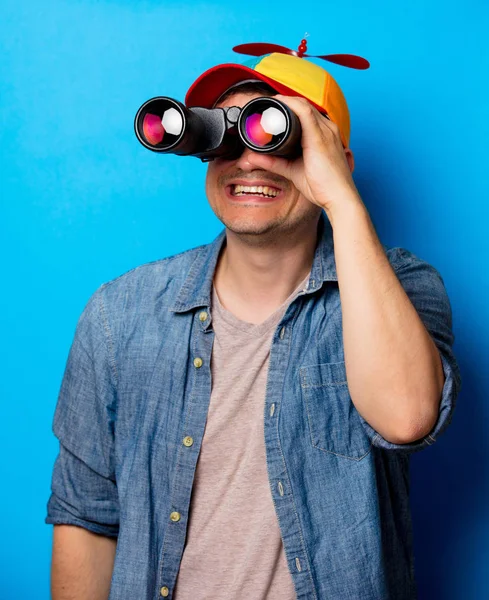 Joven empollón con sombrero de noob usando unos prismáticos — Foto de Stock