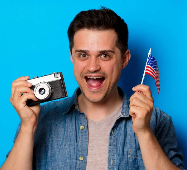 Jovem homem com câmera vintage e uma bandeira americana — Fotografia de Stock