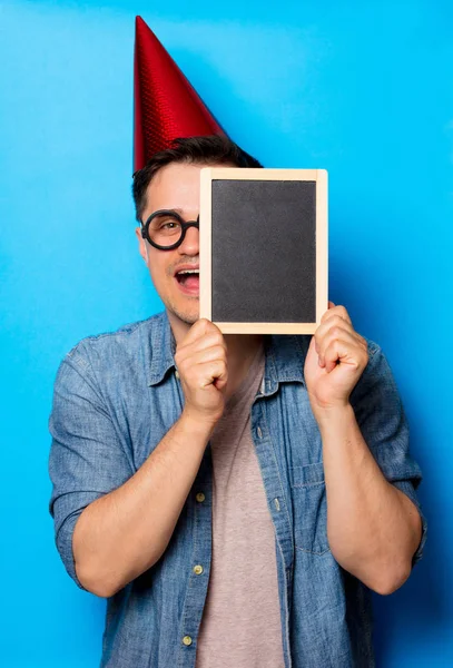 Young man in birthday hat with blackboard — Stock Photo, Image