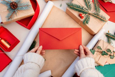 Noel hediyesi paketlerken elinde bir zarf tutan kadın.