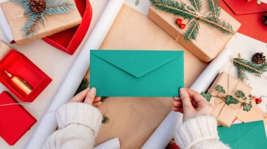 Noel hediyesi paketlerken elinde bir zarf tutan kadın.