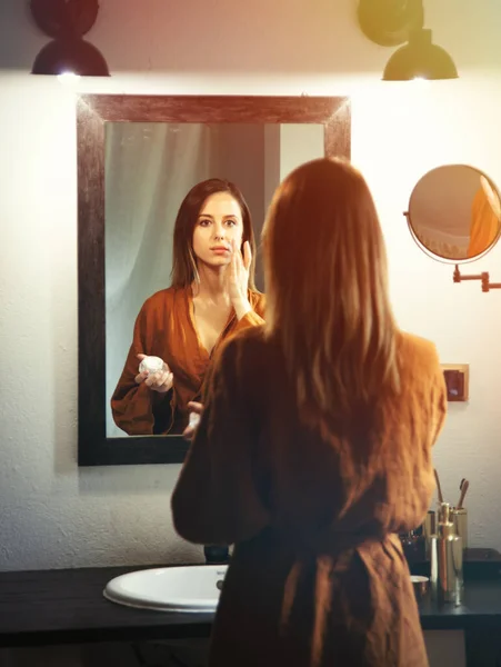 Женщина мажет лосьон в ванной комнате — стоковое фото