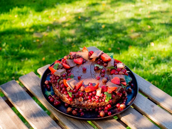 Chocolate and strawberry cake on a wooden table on backyard — Stock Photo, Image