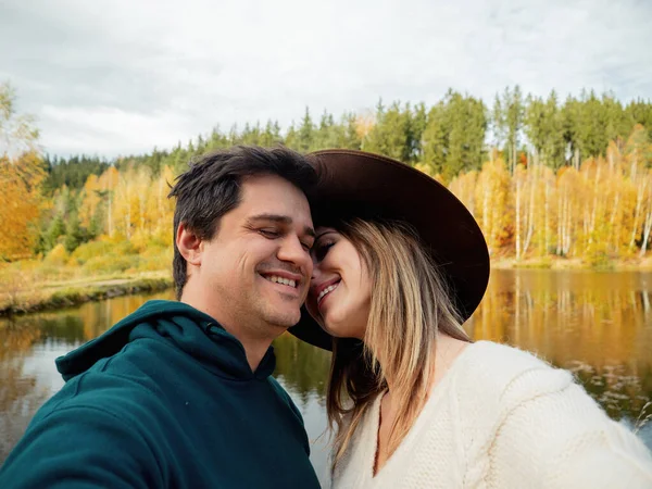 Jovem casal ternamente abraçando no lago e tirar uma selfie — Fotografia de Stock