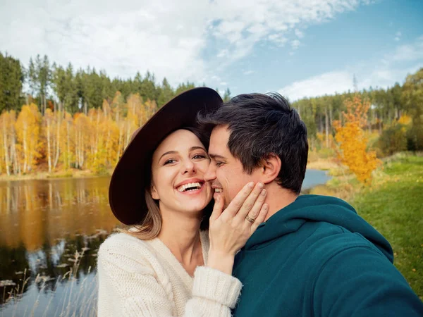 Young couple tenderly hugging on the lake and take a selfie — Stock Photo, Image