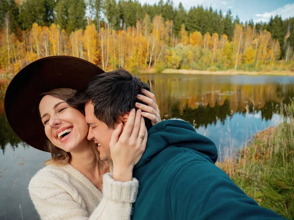 Young couple tenderly hugging on the lake and take a selfie — Stockfoto