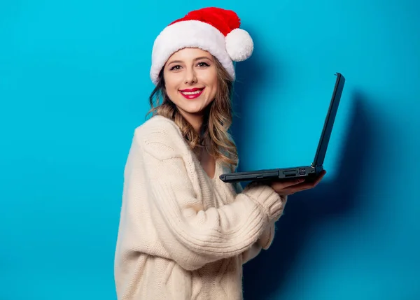 Bella donna in cappello di Natale con computer portatile su ba blu — Foto Stock